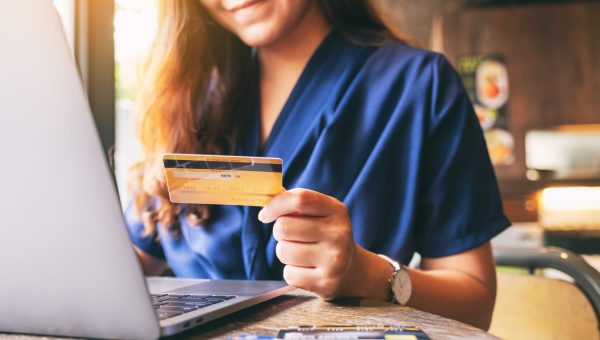 Closeup image of a business woman holding credit card while using laptop computer