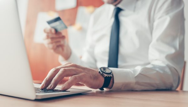 Businessman completing e-banking transaction using laptop computer and credit card, selective focus