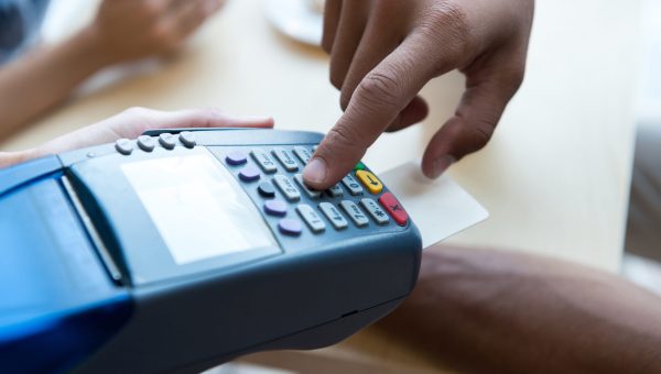 close-up partial view of person paying by credit card and terminal