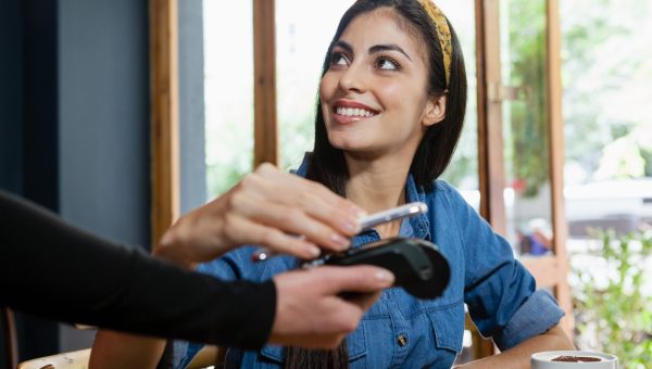 Smiling woman making payment on credit card reader at cafe shop